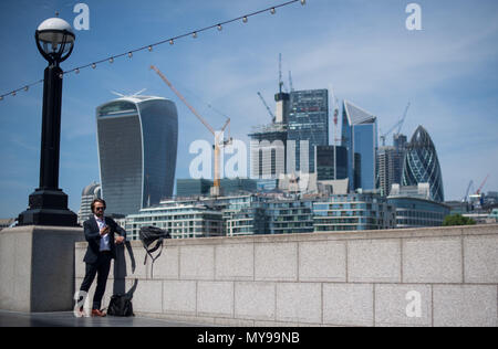 Un homme se tient au soleil avec vue sur la ville quartier financier de Londres. Banque D'Images