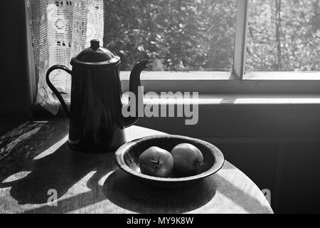 Vintage coffee pot et les deux tomates dans la plaque métallique sur la table ronde à l'intérieur rétro. Le noir et blanc Banque D'Images
