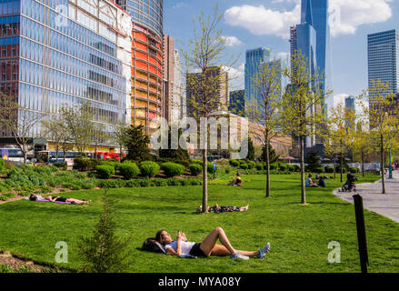 Les gens se détendre sur l'herbe dans le sud de Manhattan, un immeuble du World Trade Centre.en arrière-plan, New York City, USA Banque D'Images