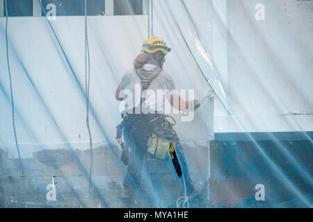 Ouvriers ascending grand bloc d'appartement en Espagne comme il peint avec rouleau. Banque D'Images