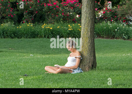 Une femme lisant sur un après-midi de juin dans la région de Hudson River Park, New York City. Banque D'Images