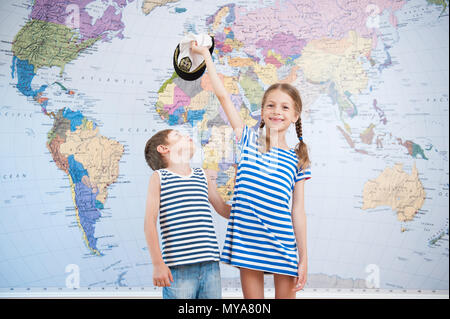 Handsome young girl in striped shirt marin et garçon jouant sur world map background Banque D'Images