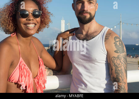 Couple mixte a couru sur la plage ensoleillée en été locations Banque D'Images