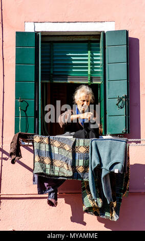 Une femme âgée à traîner les vêtements pour les faire sécher, l'île de Burano, Venise, Italie Banque D'Images