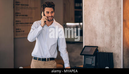 Young businessman standing in a cafe et parlant au téléphone. Restaurant manager de passer un appel téléphonique. Banque D'Images