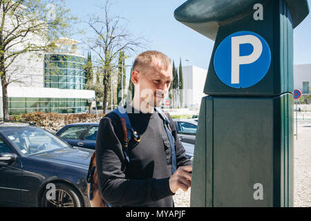 Un homme paie pour le stationnement à l'aide d'une machine spéciale pour payer à Lisbonne au Portugal. Banque D'Images