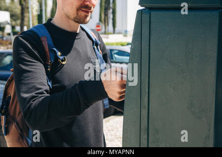 Un homme paie pour le stationnement à l'aide d'une machine spéciale pour payer à Lisbonne au Portugal. Banque D'Images