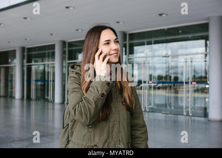 Belle jeune fille touristiques à l'aéroport ou à proximité du centre commercial ou la poste, un taxi ou en parlant sur un téléphone cellulaire ou de parler à des amis u Banque D'Images