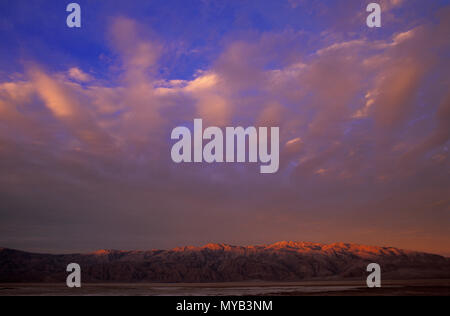 Lever du soleil dans la vallée de la mort, avec une chaîne de montagnes atteignant tout juste avec motif nuage spectaculaire, Death Valley, CA, USA Banque D'Images