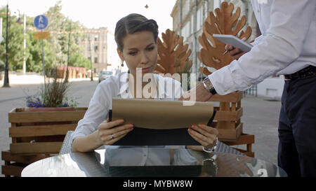 Jolie femme de passer commande pour le serveur dans le menu au café Banque D'Images