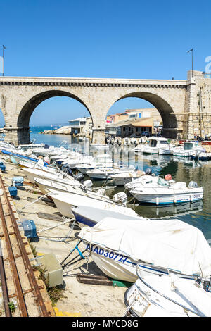 Le petit port de pêche du Vallon des Auffes par un matin ensoleillé avec ses nombreux bateaux et le pont-route de la Corniche Kennedy dans l'arrière-plan. Banque D'Images