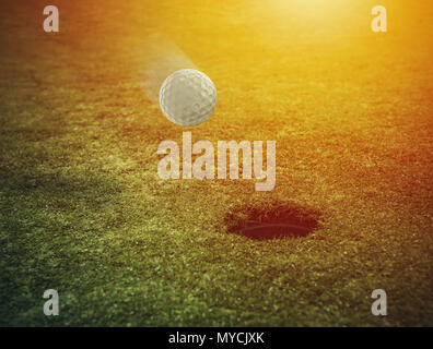 Balle de golf près du trou dans un champ d'herbe Banque D'Images