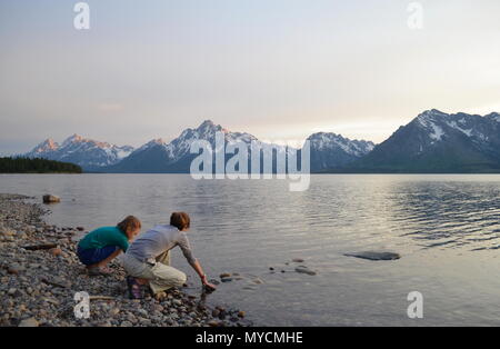 Deux jeunes filles, jouant sur la rive du lac à Grand Teton National Park au coucher du soleil, le Wyoming. Banque D'Images