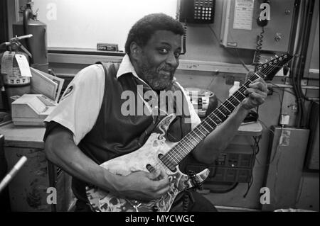 Un nouveau yoyk city Subway train ticket sales officer, joue de la guitare au travail dans son émission de billet stand. Manhattan, New York City, USA, Banque D'Images