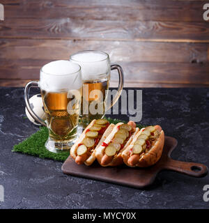 Photo de deux chopes de bière en mousse, l'herbe verte avec le football, hot-dogs Banque D'Images