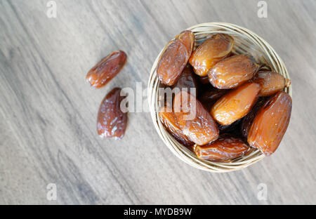 Dates de fruits frais dans un panier Bol sur table en bois de noyer Banque D'Images