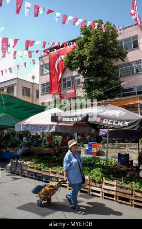 Selcuk, Turquie. 22 mai, 2018. 22 mai 2018, la Turquie, Selçuk : une femme passe les étals de marché et un bâtiment avec des drapeaux turcs. - Pas de service de fil - Crédit : Jens Kalaene Zentralbild-/dpa/dpa/Alamy Live News Banque D'Images