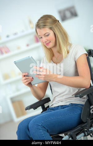 Fille sur le fauteuil roulant à l'aide d'une tablette Banque D'Images