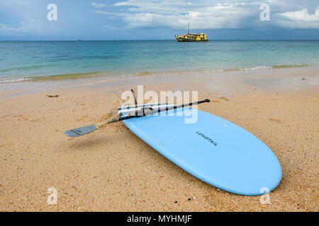 2 mai 2018 - L'archipel de Myeik, Myanmar. Paddleboard sur plage déserte avec bateau de croisière en arrière-plan Banque D'Images