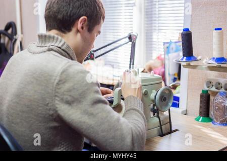 Professionnel hommes skinner, fourreur à l'aide de la machine à coudre spéciale pour coudre la peau de fourrure à l'atelier, atelier. La mode et le travail du cuir concept Banque D'Images