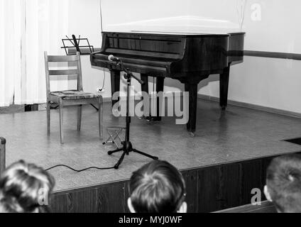 Photo en noir et blanc. Sur la scène est un piano et le public est en attente pour le concert. Banque D'Images