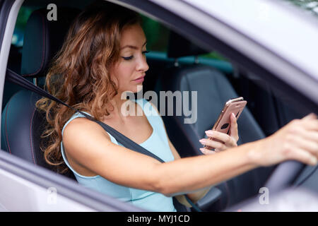 Femme au volant pendant l'utilisation de téléphone mobile Banque D'Images