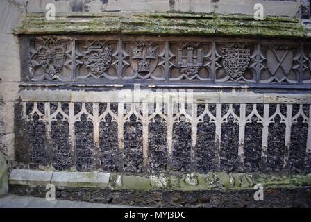 Conception avec boucliers héraldiques sculptés sur l'extérieur d'un vieux mur de l'église à Norwich, Angleterre. Banque D'Images