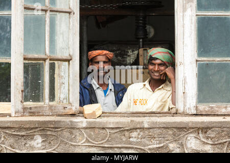 Deux travailleurs en regardant par la fenêtre à l'Kolukkumalai, usine de thé de Munnar, Kerala, Inde. Banque D'Images