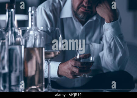 Close-up de triste et solitaire boissons boire du vin dans une pièce sombre Banque D'Images