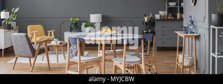Panorama de l'intérieur gris avec table à manger à côté d'un fauteuil en bois, jaune Banque D'Images