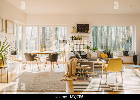 Chaise jaune à rayures à l'intérieur de tapis dans l'espace ouvert avec table à manger près de window Banque D'Images