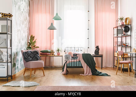 Oreiller noeud rose pastel sur un fauteuil dans la chambre de jeune fille avec les lampes d'intérieur et rideaux Banque D'Images