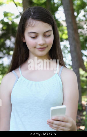 Happy smiling young woman reading a text message sur un smartphone. Selective focus sur l'adolescence. Banque D'Images