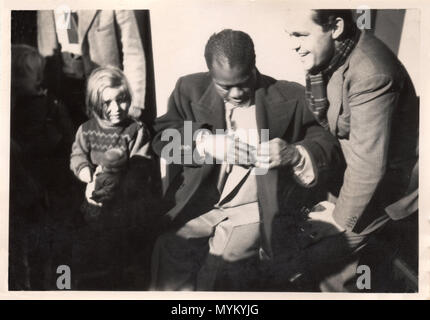 Photographie informelle de Louis Armstrong avec smiling man et petite fille avec sa poupée. Photographie fait partie d'un album privé du musicien danois, et a probablement été fabriqué en 1933, Armstrong a joué avec des musiciens locaux de Copenhague, y compris l'homme sur la droite. La petite fille est sa fille ; leurs noms ne sont pas enregistrés. Banque D'Images