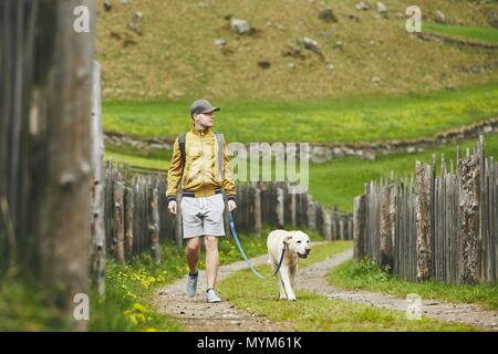 Touriste avec chien dans la campagne. Jeune homme marchant avec le labrador retriever sur chemin de terre. Banque D'Images