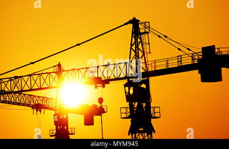 Deux grues de construction d'ossature contre le soleil couchant Banque D'Images