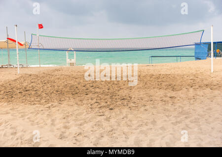 Filet de volley-ball sur une plage tropicale de sable déserte de l'océan calme avec toile de fond sur un jour nuageux dans un concept de vacances d'été Banque D'Images