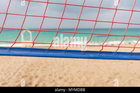 Close up sur un filet de volley-ball orange sur une plage de sable donnant sur une mer calme sur un jour nuageux Banque D'Images