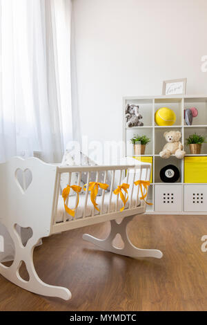 Tiré d'un lit d'enfant dans un décor blanc et jaune chambre de bébé Banque D'Images