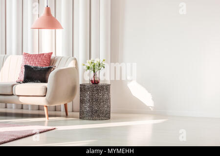 Salon simple intérieur avec coussins rose et gris sur canapé beige et roses sur métal Banque D'Images