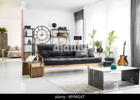 Vase vert foncé en face d'un canapé et table en bois avec coffre à l'intérieur de l'homme vacances avec guitare Banque D'Images