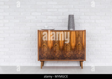 Commode en bois ancien, debout dans la lumière avec la texture du mur de brique intérieur Banque D'Images