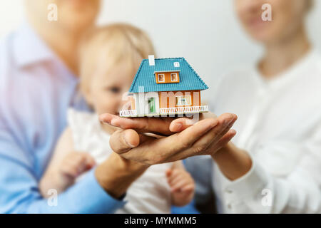 Nouvelles Accueil Concept - jeune famille avec modèle à l'échelle de la maison de rêve dans les mains Banque D'Images