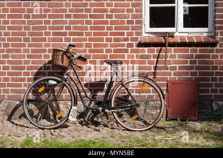 Vélo Vintage appuyée sur un mur de brique d'une maison Banque D'Images