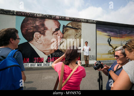 Berlin. L'Allemagne. Les touristes posent pour des photos en face de l'une des autres sections du Mur de Berlin à l'East Side Gallery. Des touristes posent pour ph Banque D'Images