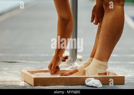 Gymnaste frotte la craie sur ses jambes en gymnastique Exercices sur poutre Banque D'Images