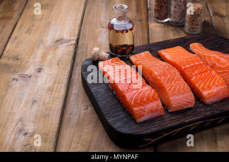 Darnes de saumon et les épices dans de petites bouteilles. Préparation des aliments sains et savoureux. Fond de bois et de la place pour le texte. Les fruits de mer. Alimentation saine. Banque D'Images