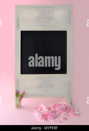 Blank chalkboard with jolie rose boutons de rose et des pétales tourné en un soft focus pour l'utilisation dans le texte sur les annonces, avis et massages Banque D'Images