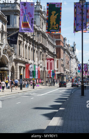 In a street busy with people colourful banners hang above the road in Piccadilly. Advertising banners hang outside Royal Academy, Burlington House Banque D'Images