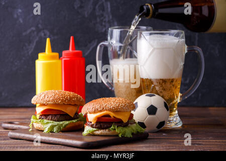 Image de deux hamburgers, lunettes, ballon de soccer, ketchup Banque D'Images